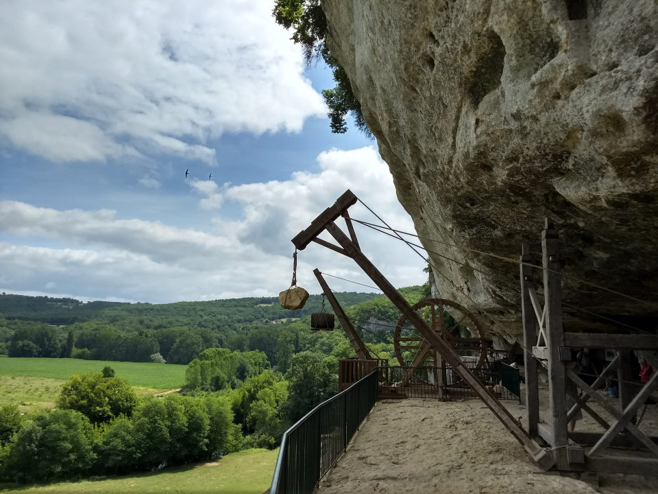 There are replicas of several different types of cranes they built to lift up heavy loads from the Vézère to their village. As far as I remember 50+ meters - the Vézère is hidden by the trees below.